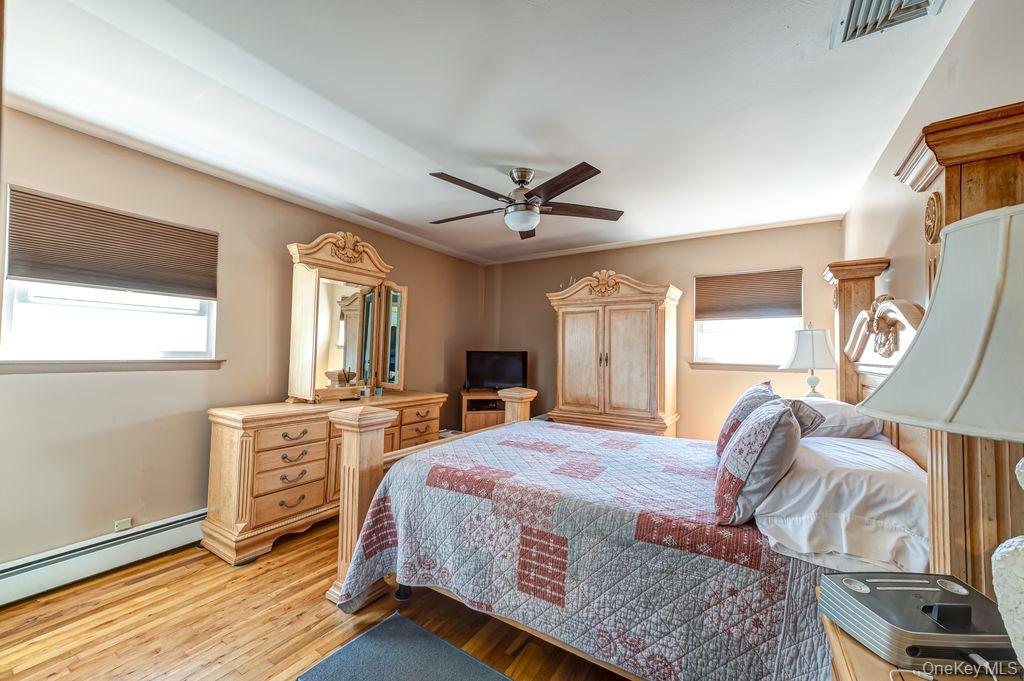 89 Cheltenham Road West Babylon, NY 11704 - Photo 13 of 26 a bedroom with a bed and dresser with wooden floor