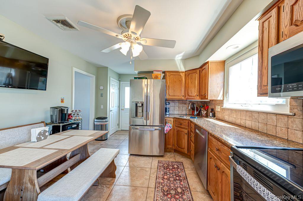 89 Cheltenham Road West Babylon, NY 11704 - Photo 10 of 26 a large kitchen with stainless steel appliances granite countertop a sink and a stove