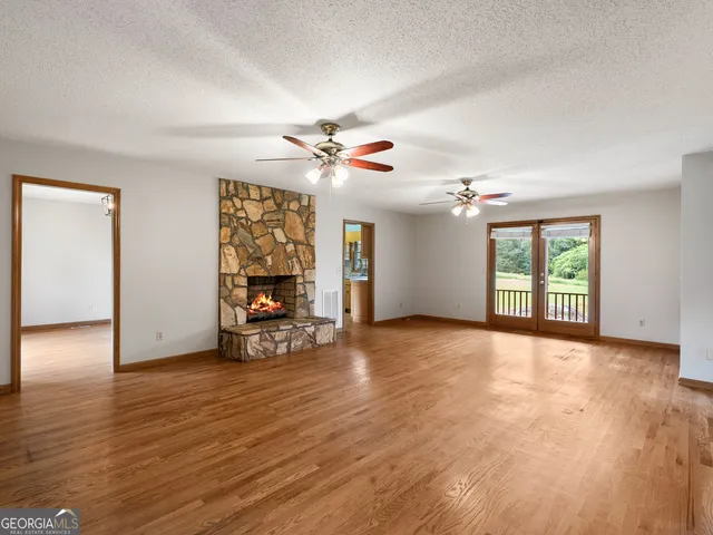 a view of an empty room with window and wooden floor