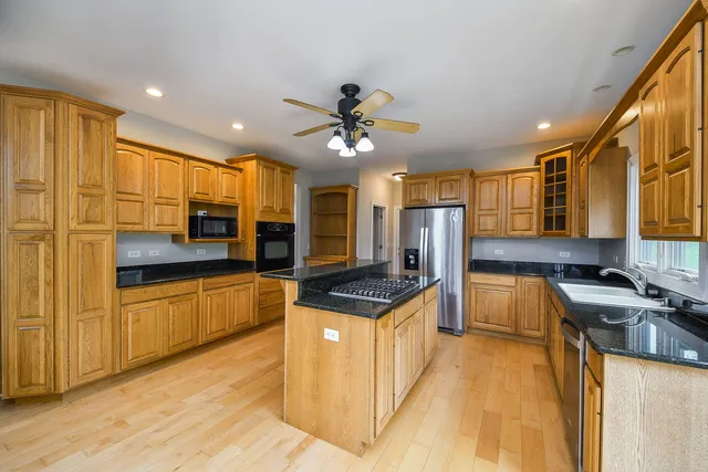a kitchen with stainless steel appliances granite countertop a stove a sink dishwasher and a fireplace with wooden floor