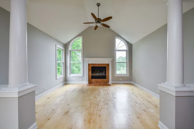 a view of empty room with wooden floor and fan