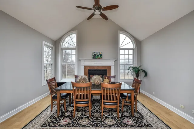 a view of a livingroom with a fireplace a ceiling fan and wooden floor