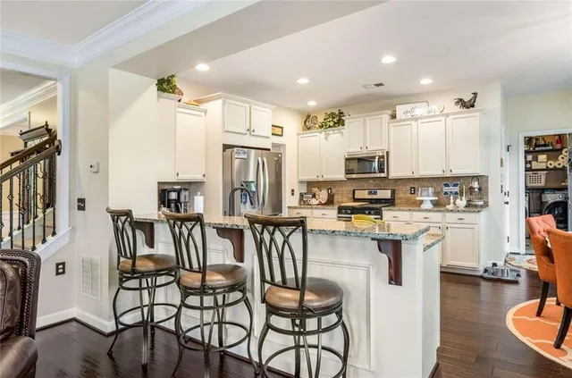 a kitchen with stainless steel appliances kitchen island granite countertop a dining table chairs refrigerator and sink