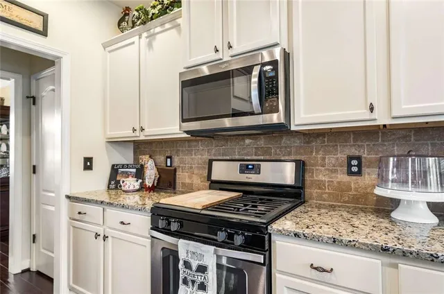 a kitchen with granite countertop white cabinets and stainless steel appliances