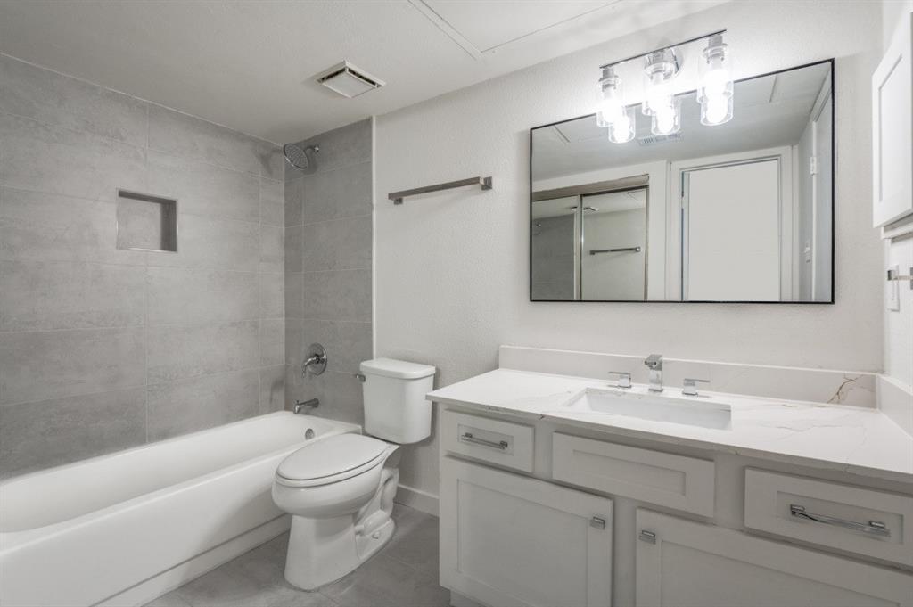 5550 Spring Valley Road, Unit D31 Dallas, TX 75254 - Photo 8 of 20 a bathroom with a toilet a sink a tub and a mirror