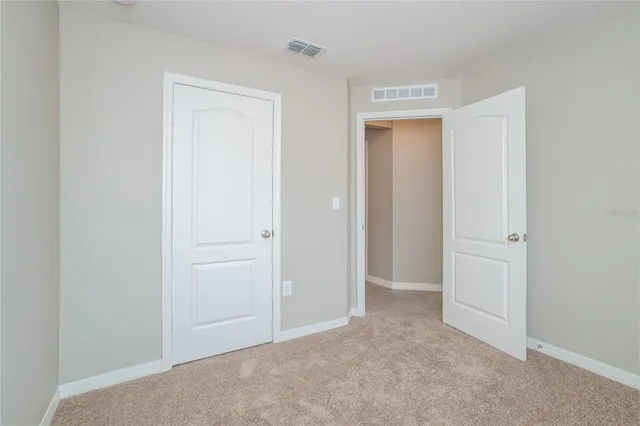 a view of an empty room with closet and a window