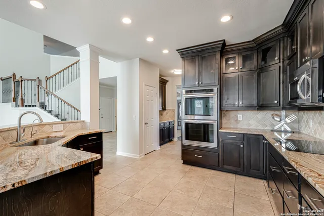 a kitchen with stainless steel appliances granite countertop a sink and a refrigerator