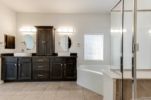 a spacious bathroom with a tub sink and mirror