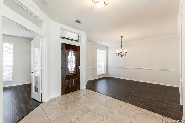 an empty room with wooden floor cabinet and windows