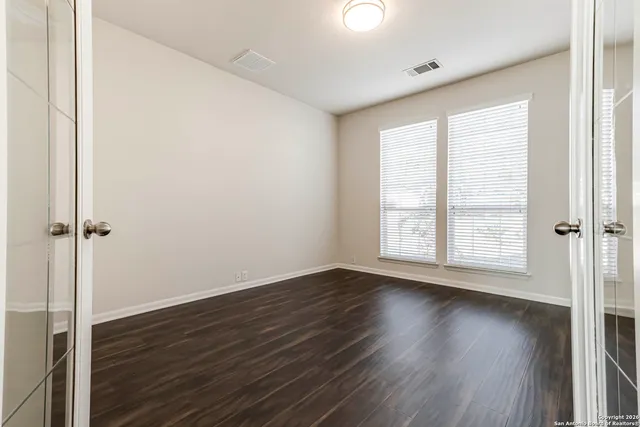 an empty room with wooden floor and windows