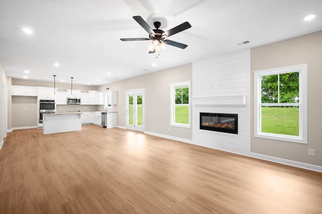 a view of an empty room with a kitchen and a window
