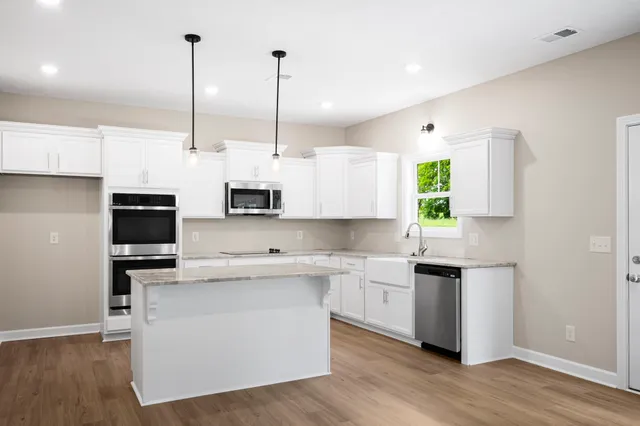 a kitchen with stainless steel appliances kitchen island a white cabinets and wooden floor