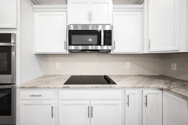 a kitchen with granite countertop white cabinets and a stove