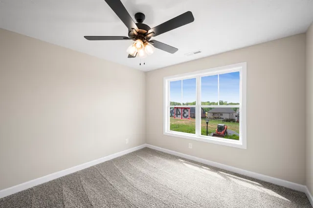 an empty room with windows and ceiling fan