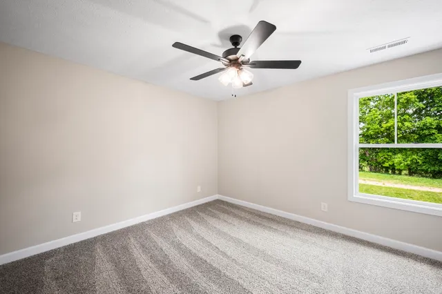 an empty room with a window and a fan