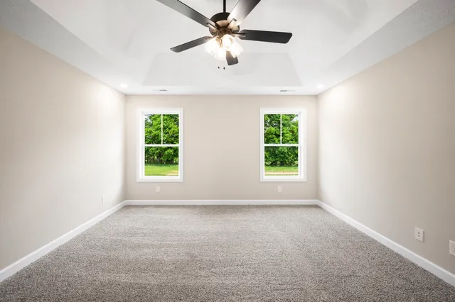 an empty room with windows and a ceiling fan