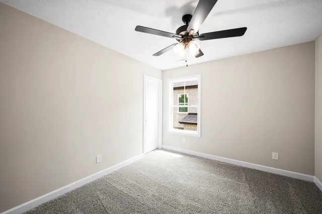 an empty room with a window and a fan