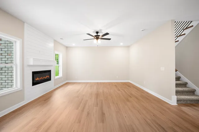 wooden floor in an empty room with a fireplace and a chandelier