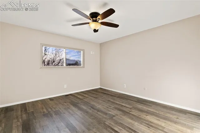 an empty room with wooden floor and ceiling fan