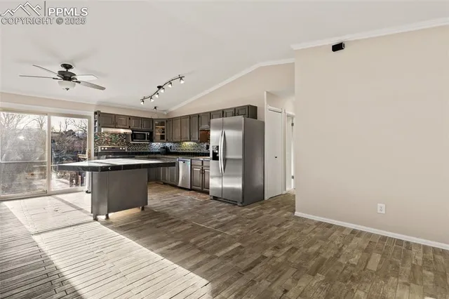 a large kitchen with stainless steel appliances kitchen island a large counter top and wooden floors