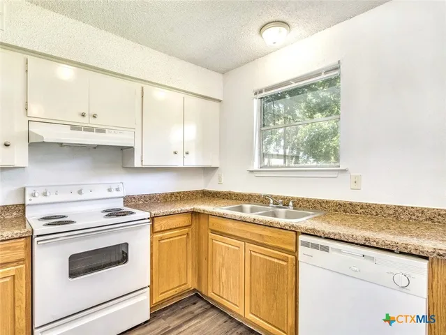 a kitchen with granite countertop white cabinets and white appliances