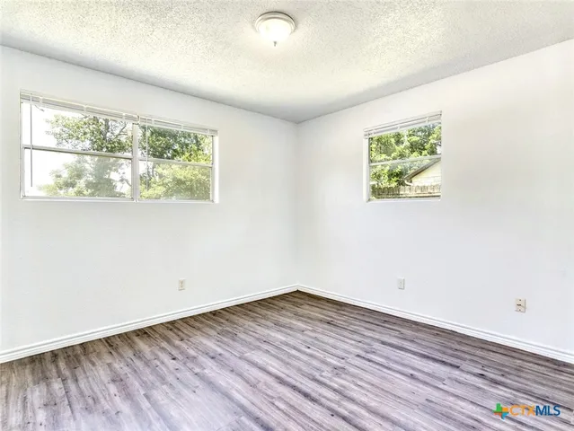 an empty room with wooden floor and window