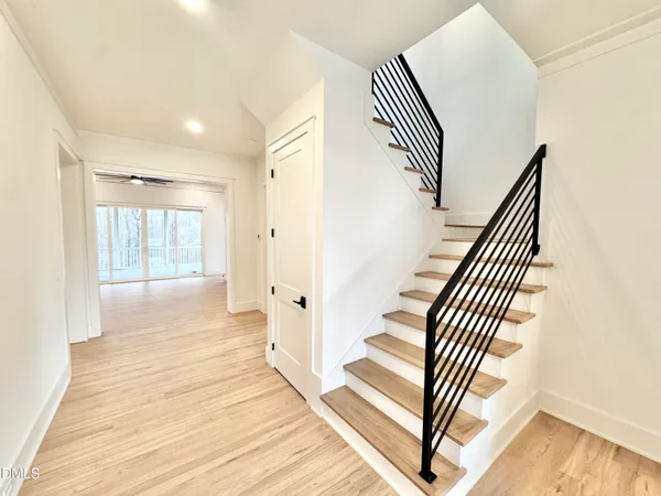 a large white kitchen with a large center island wooden floor and stainless steel appliances