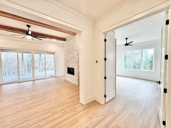 a large white kitchen with wooden floor and a window