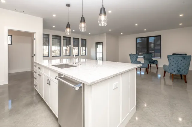 a large white kitchen with a large island in the center
