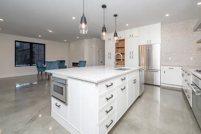 a kitchen with stainless steel appliances kitchen island granite countertop a refrigerator and a sink