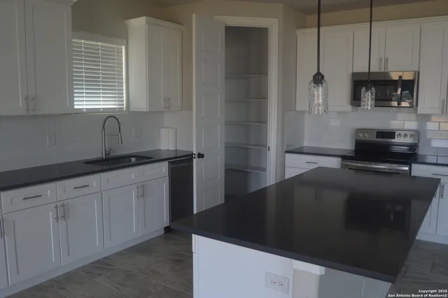 a kitchen with granite countertop a refrigerator and a sink