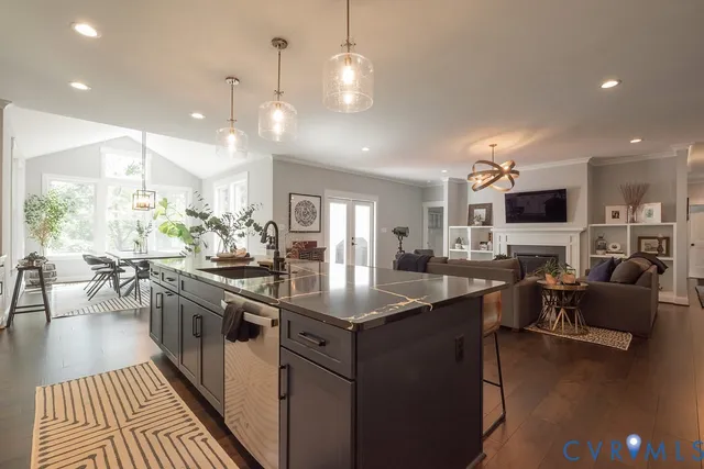 a kitchen with stainless steel appliances granite countertop a stove top oven a sink dishwasher a dining table and chairs with wooden floor