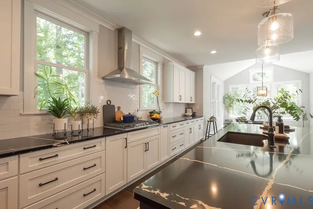 a kitchen with stainless steel appliances kitchen island granite countertop a large window and white cabinets