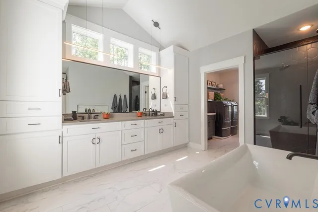 a spacious bathroom with a granite countertop double vanity sink a mirror and next to a window