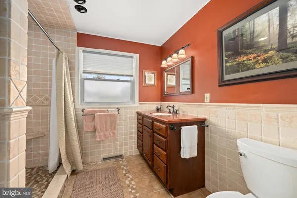 a bathroom with a granite countertop sink a toilet a mirror and shower