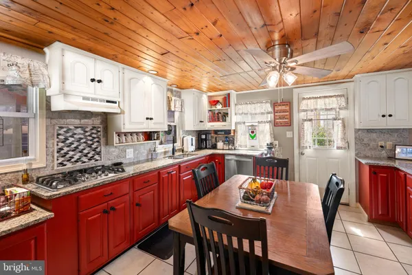 a kitchen with stainless steel appliances granite countertop a sink a stove a dining table and chairs with wooden floor
