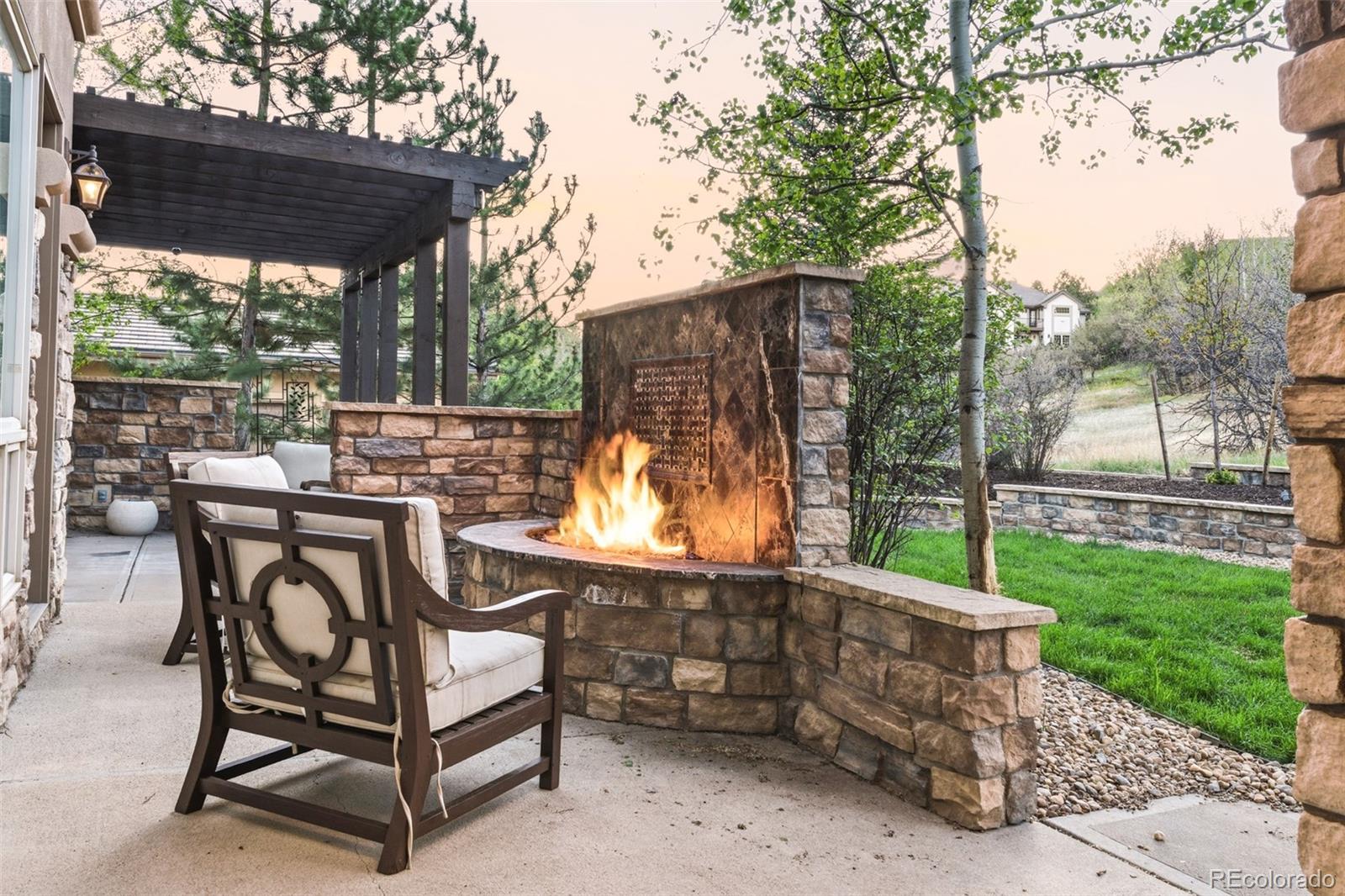 981 Buffalo Ridge Road Castle Pines, CO 80108 - Photo 42 of 49 a view of a patio with table and chairs under an umbrella with a large tree
