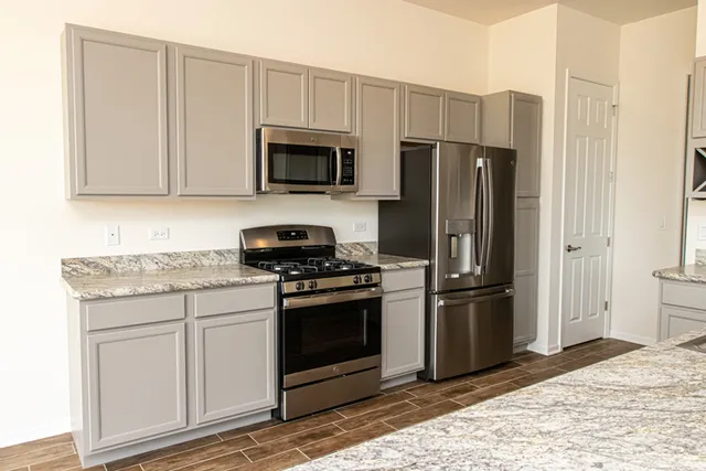 a kitchen with stainless steel appliances granite countertop a stove a refrigerator and a microwave
