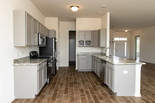 a kitchen with stainless steel appliances granite countertop a stove top oven a sink a refrigerator and white cabinets
