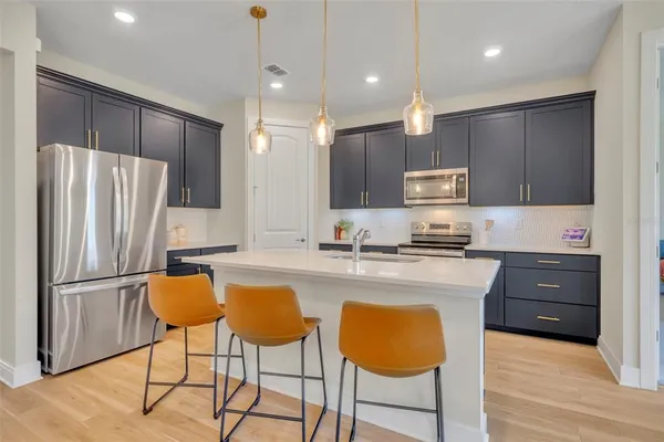 a kitchen with kitchen island granite countertop wooden cabinets and refrigerator