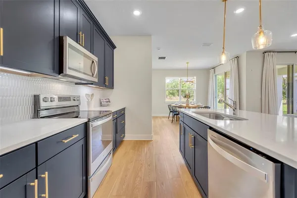 a kitchen with stainless steel appliances granite countertop a sink a stove and a wooden floors