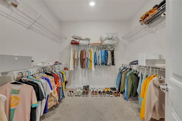 a view of walk in closet with clothes and shoes