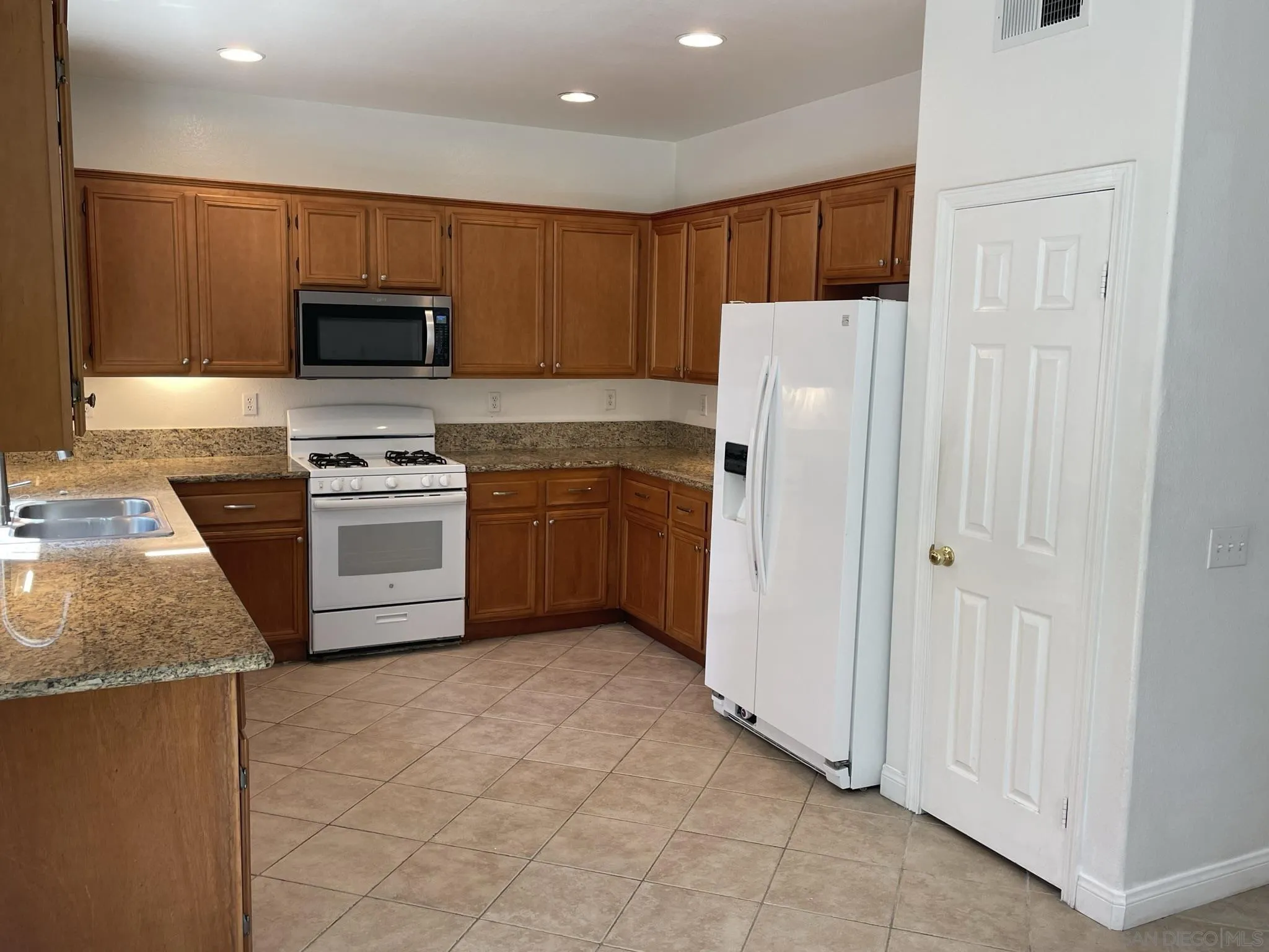 348 Monte Vista Way Oceanside, CA 92057 - Photo 5 of 20 a kitchen with stainless steel appliances granite countertop wooden cabinets a stove a sink and a refrigerator