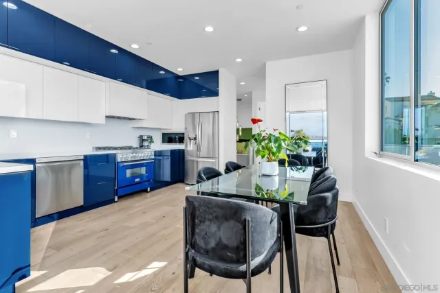 a kitchen with stainless steel appliances kitchen island granite countertop a refrigerator a stove a sink dishwasher and white cabinets with wooden floor