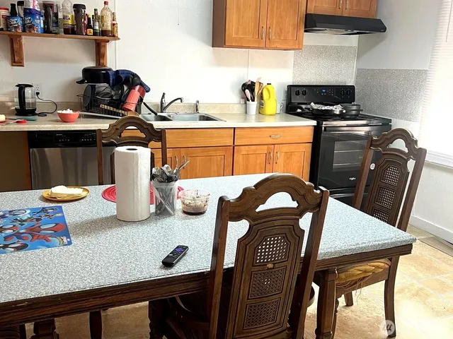a kitchen with stainless steel appliances granite countertop a table chairs and a stove