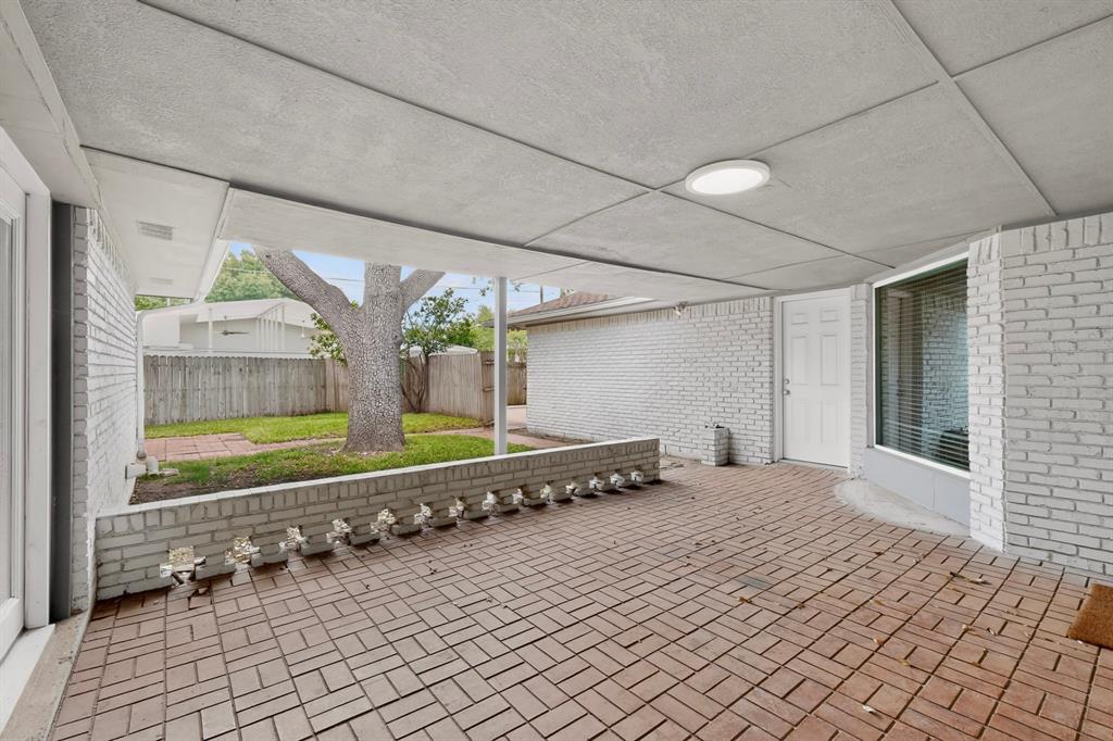 7631 Meadow Road Dallas, TX 75230 - Photo 33 of 40 A charming brick patio with a warm brick floor and white brick walls, with a view to the lush backyard tree