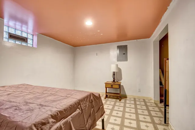 a bedroom with a bed and a lamp with the view of bathroom