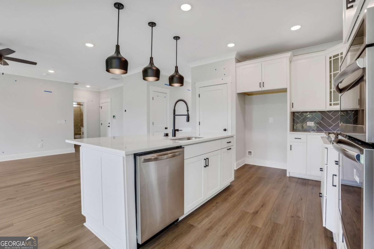 4250 Mary Ruth Way Loganville, GA 30052 - Photo 17 of 50 a kitchen with stainless steel appliances granite countertop a sink a stove a refrigerator and white cabinets with wooden floor