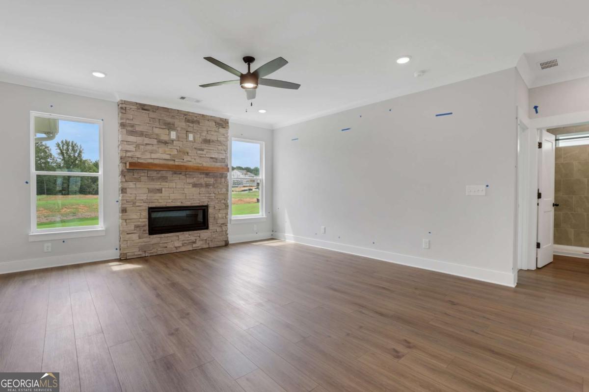 4250 Mary Ruth Way Loganville, GA 30052 - Photo 7 of 50 an empty room with wooden floor a ceiling fan a fireplace and windows