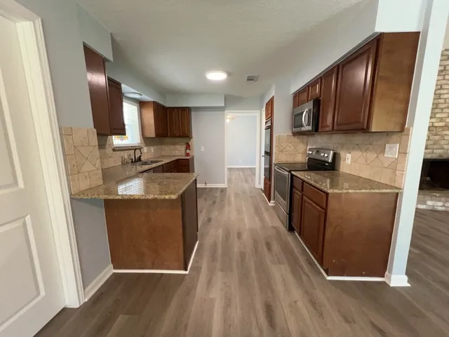 a kitchen with granite countertop wooden floors a stove top oven and granite counter tops